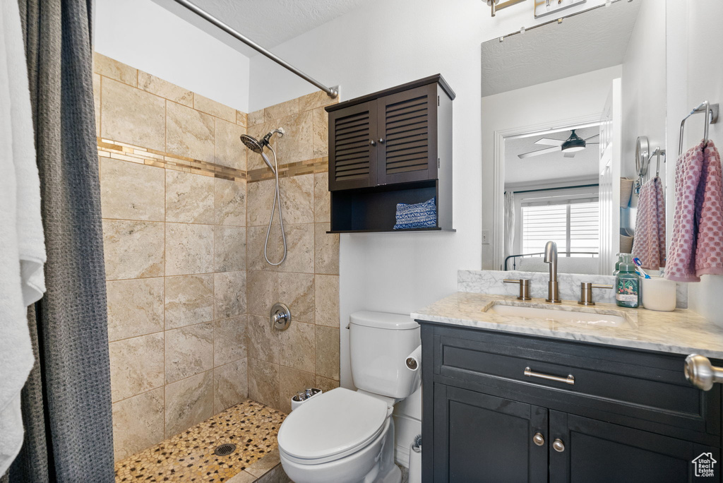 Bathroom with vanity, a tile shower, and a ceiling fan