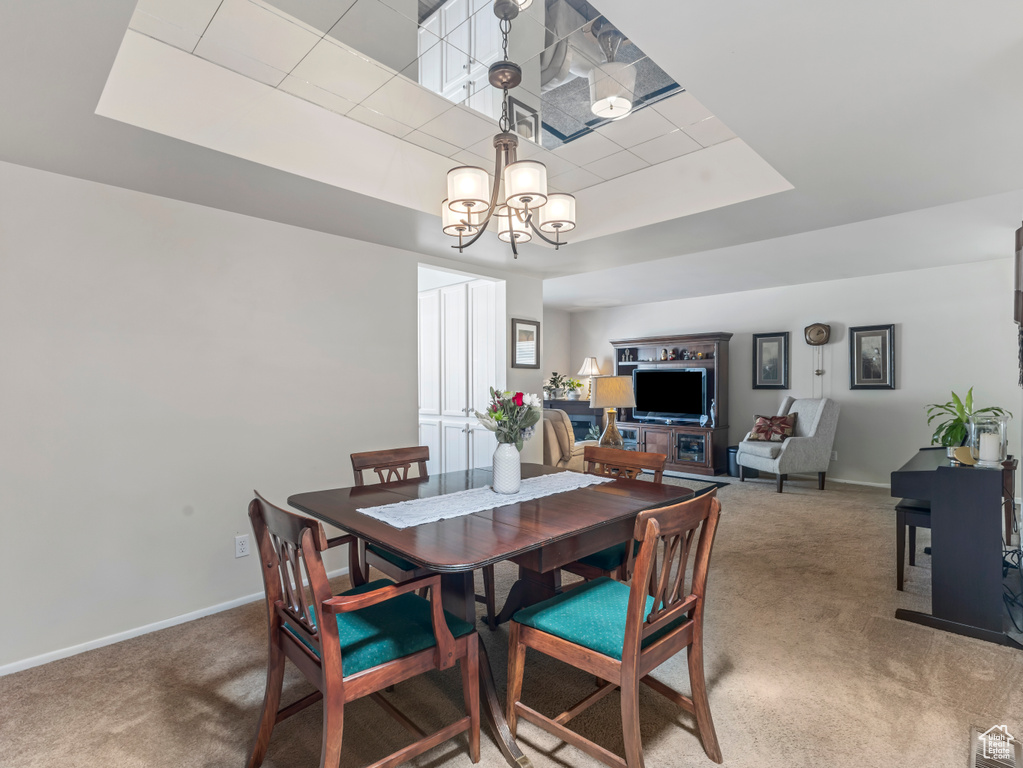 Dining area featuring carpet floors, a chandelier, and a raised ceiling