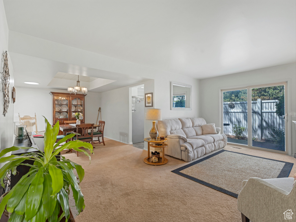 Carpeted living room with a tray ceiling and a chandelier