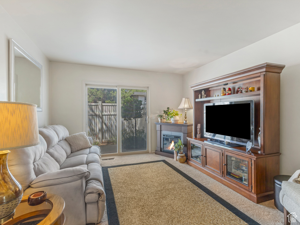 Carpeted living area featuring a glass covered fireplace