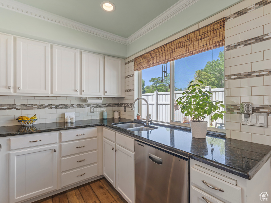 Kitchen with dishwasher, backsplash, white cabinets, dark stone counters, and crown molding