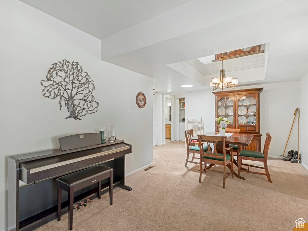Dining area featuring a chandelier, a tray ceiling, and light colored carpet