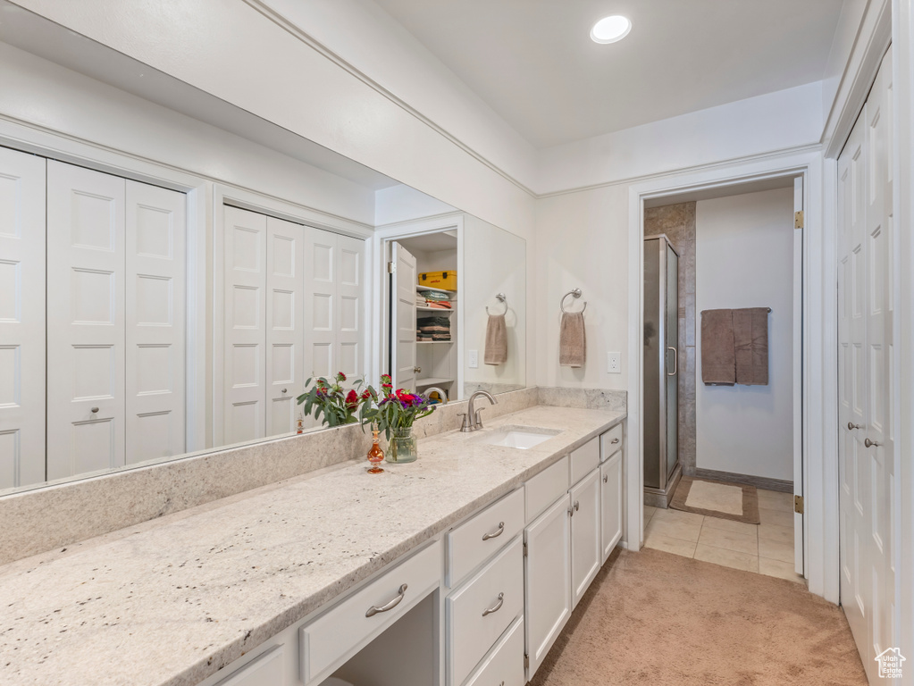 Bathroom with a closet, a shower stall, vanity, and tile patterned floors
