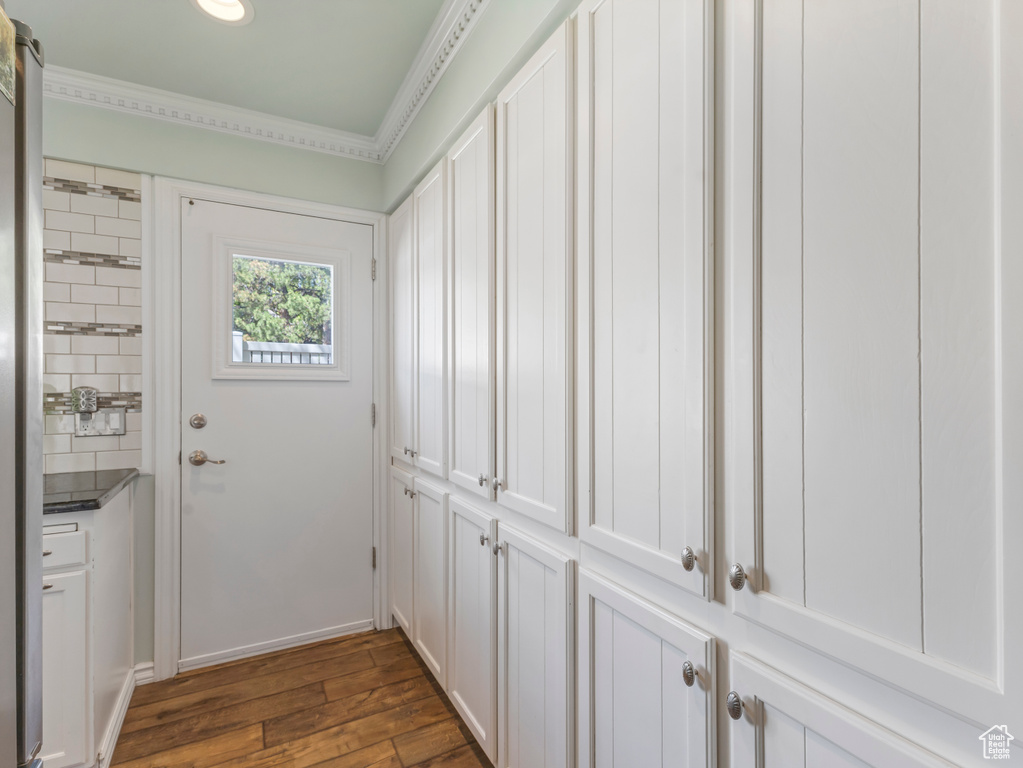 Entryway featuring dark wood-style flooring and crown molding
