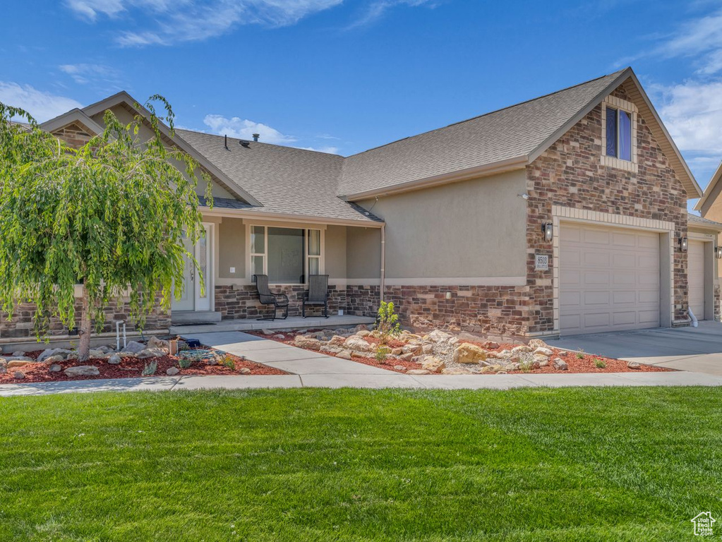 Craftsman house with stucco siding, stone siding, and a front lawn