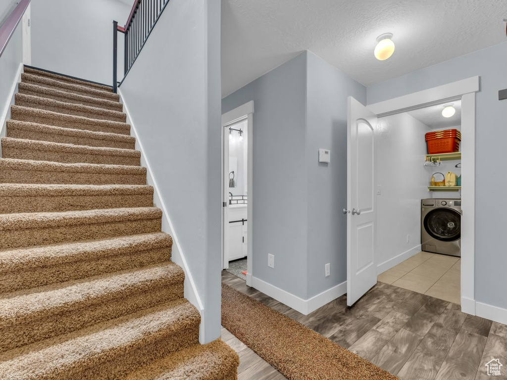 Stairs featuring washer / dryer, wood finished floors, and a textured ceiling