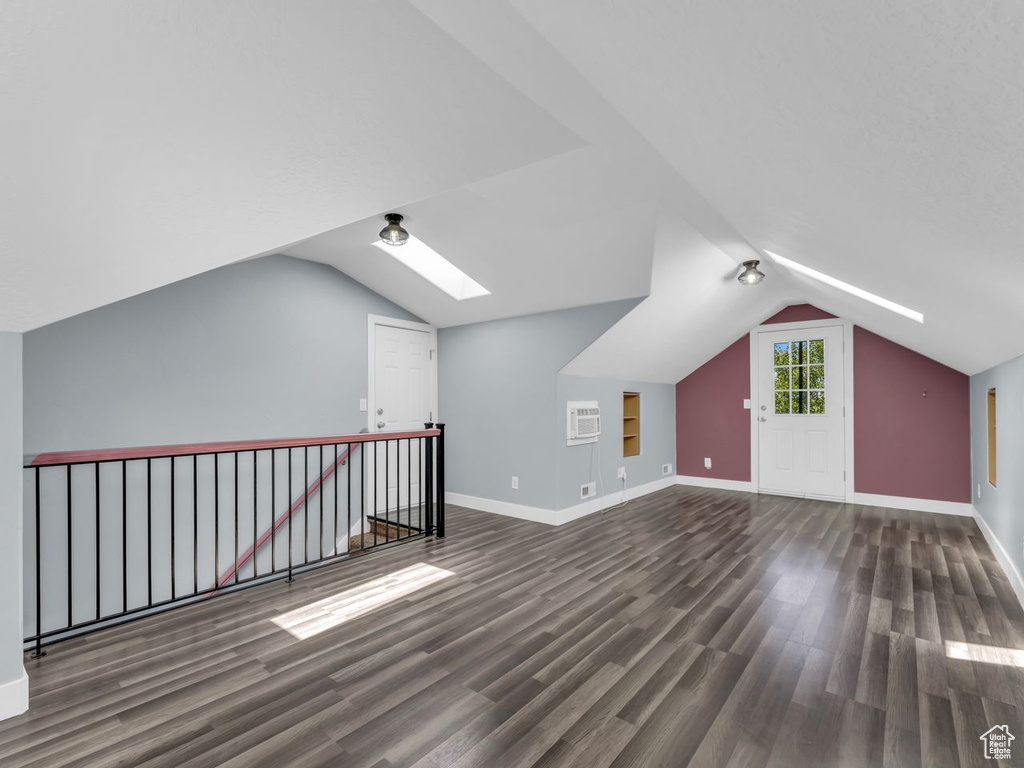 Bonus room featuring a skylight, wood finished floors, lofted ceiling, and a wall mounted air conditioner