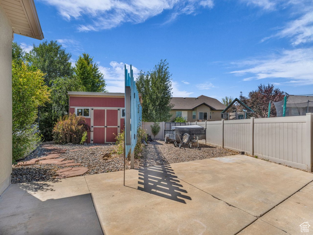 Fenced backyard with a patio area and a storage unit