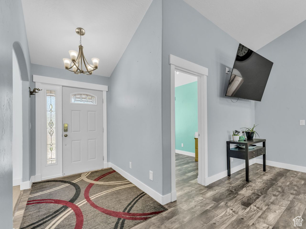 Foyer with a chandelier, lofted ceiling, wood finished floors, and arched walkways
