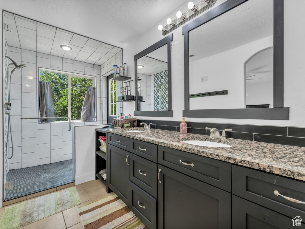 Full bathroom featuring a stall shower, double vanity, tile patterned flooring, and a ceiling fan