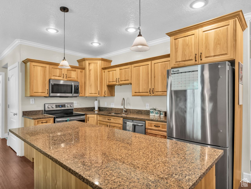 Kitchen featuring stainless steel appliances, crown molding, a center island, dark wood-style flooring, and a textured ceiling