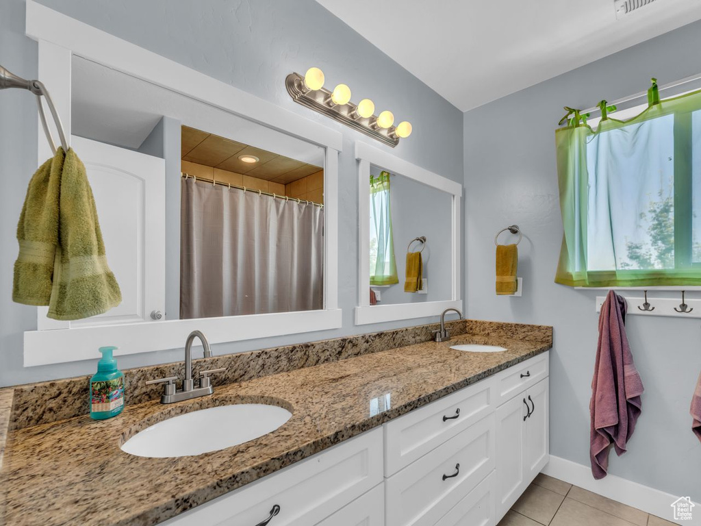 Bathroom featuring double vanity, tile patterned floors, and healthy amount of natural light