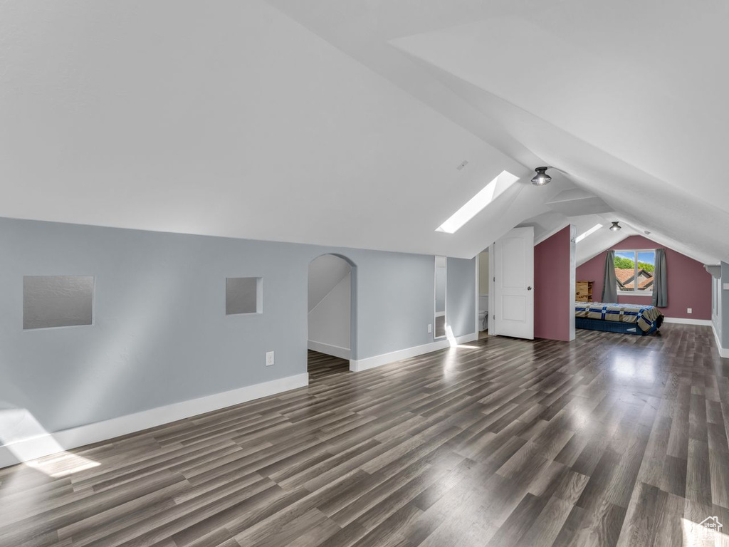 Bonus room featuring dark wood-style floors, vaulted ceiling, and a skylight