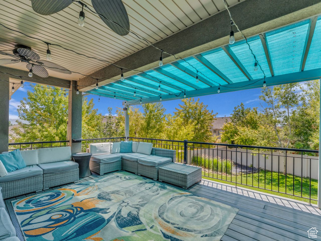 Wooden deck with an outdoor hangout area, a ceiling fan, and a pergola