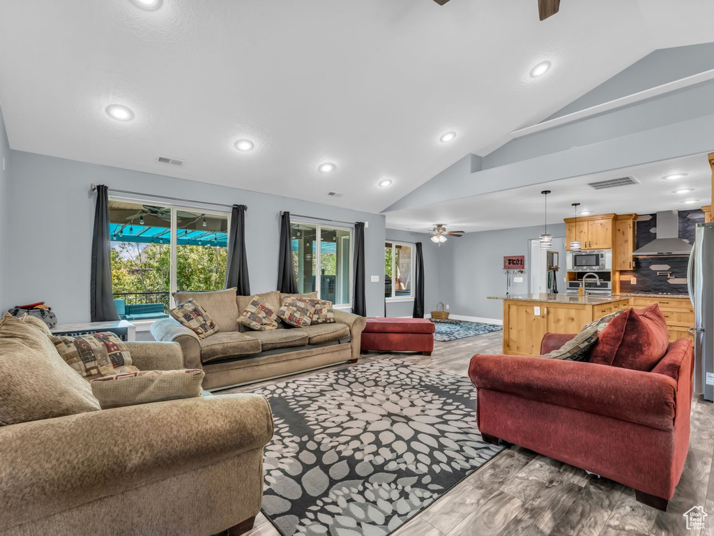 Living area with a ceiling fan, lofted ceiling, wood finished floors, and recessed lighting