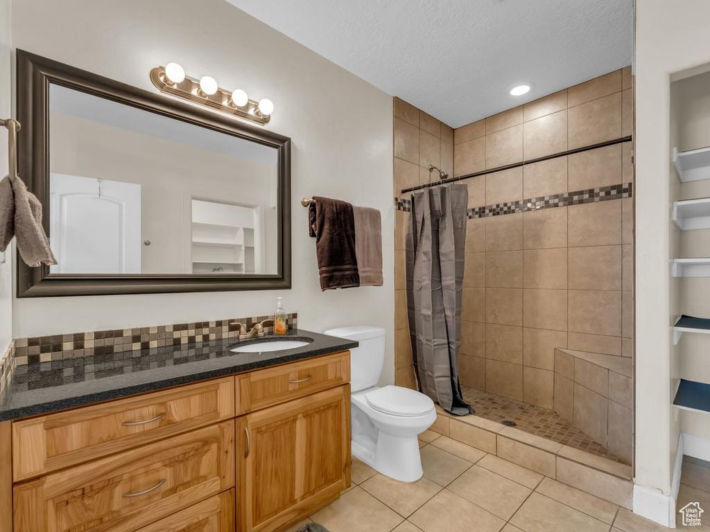 Full bath featuring vanity, a tile shower, a textured ceiling, and tile patterned flooring