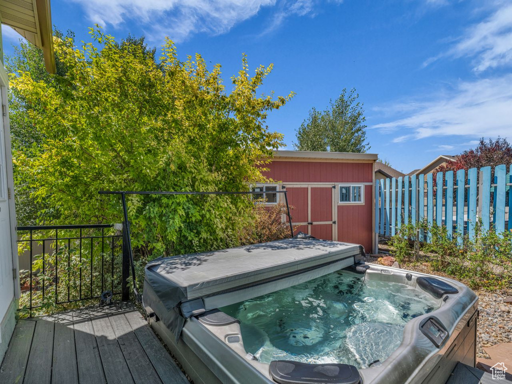 Deck featuring a covered hot tub and a storage shed