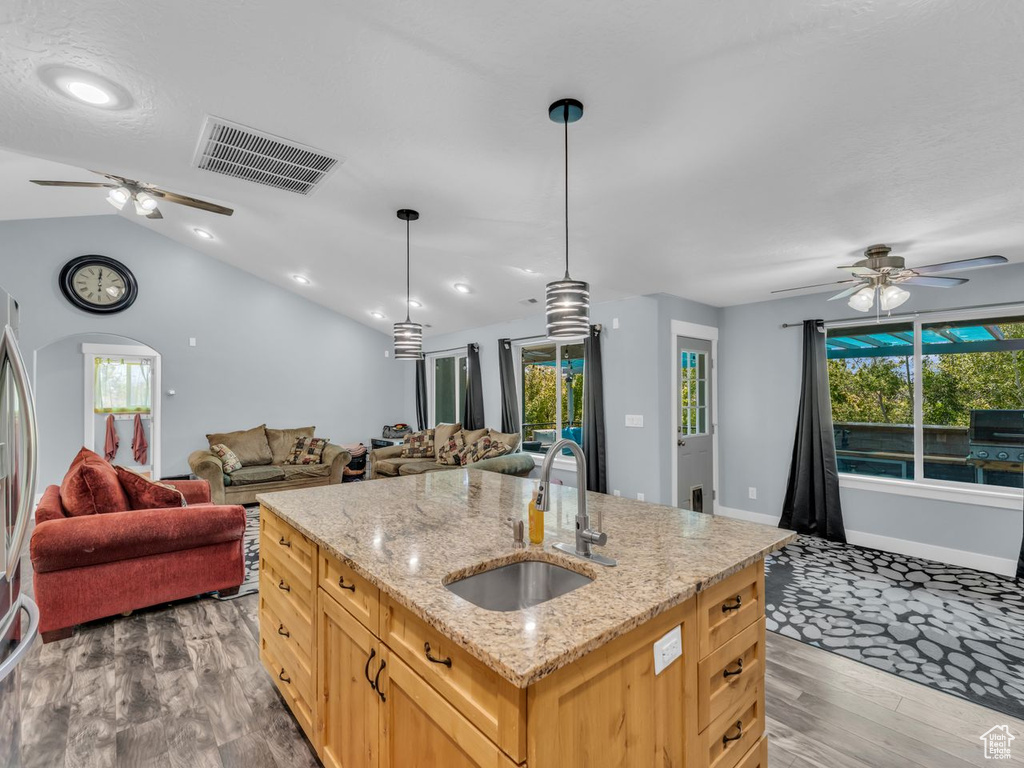 Kitchen with open floor plan, a ceiling fan, wood finished floors, light brown cabinets, and vaulted ceiling