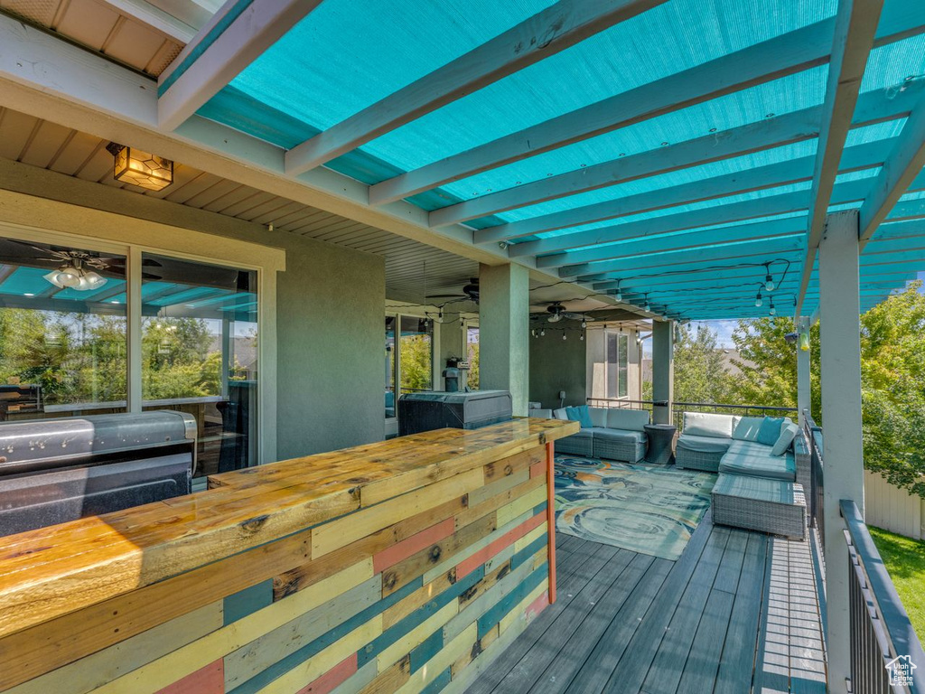 Wooden deck with an outdoor hangout area, ceiling fan, and grilling area