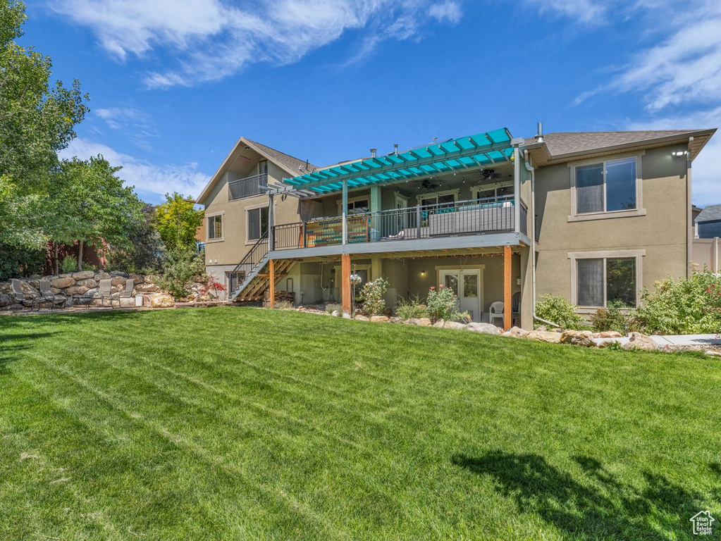 Rear view of property featuring a ceiling fan, a wooden deck, stairs, stucco siding, and a lawn