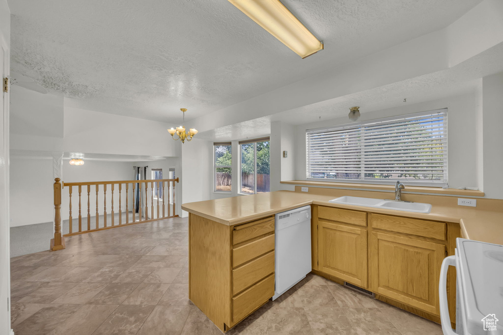 Kitchen with range, white dishwasher, a textured ceiling, light countertops, and a chandelier