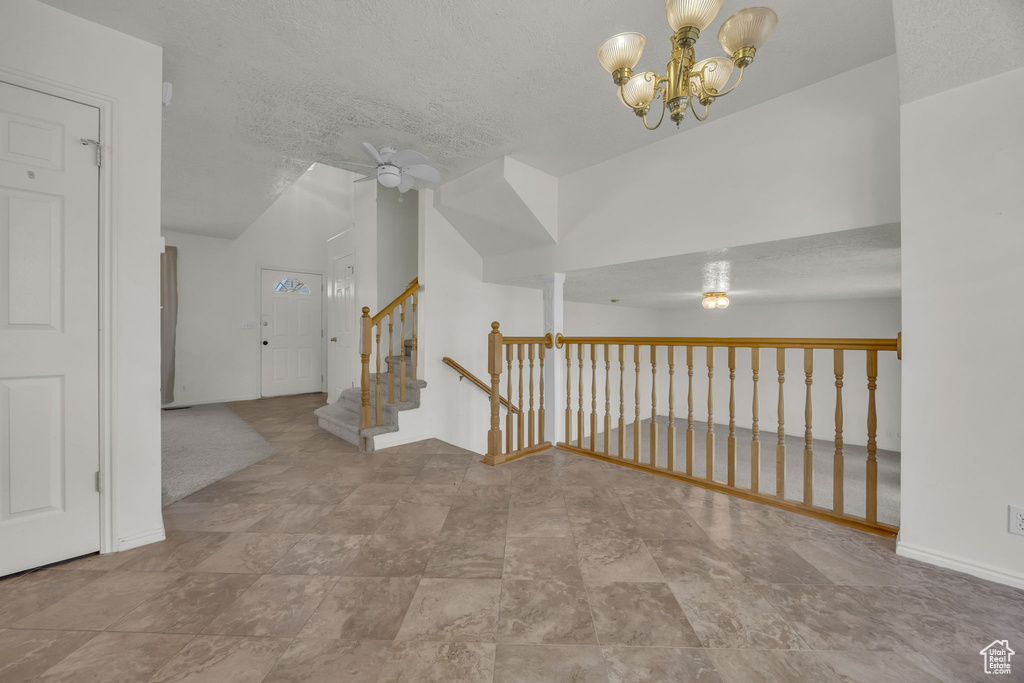 Hallway featuring a chandelier, a textured ceiling, and stairway
