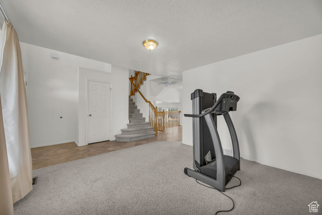Workout area featuring carpet floors, ceiling fan, and a textured ceiling