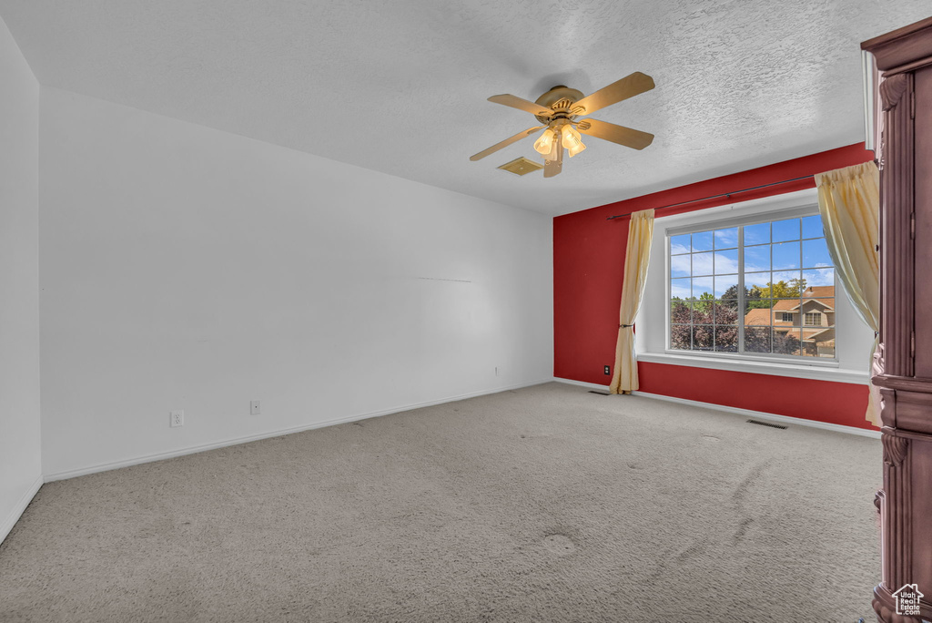 Carpeted spare room featuring a ceiling fan and a textured ceiling