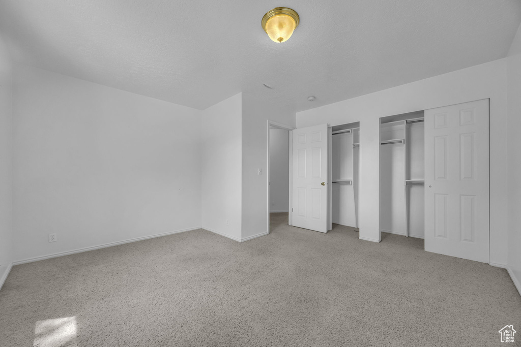 Unfurnished bedroom featuring two closets and carpet flooring