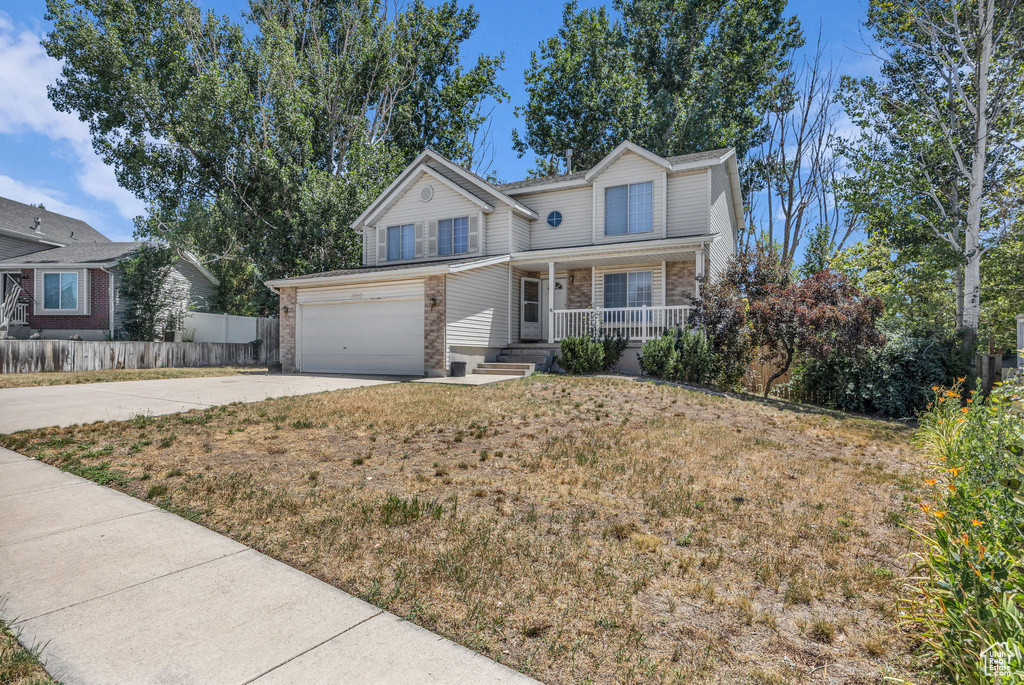Traditional-style home with a porch, concrete driveway, brick siding, and a garage