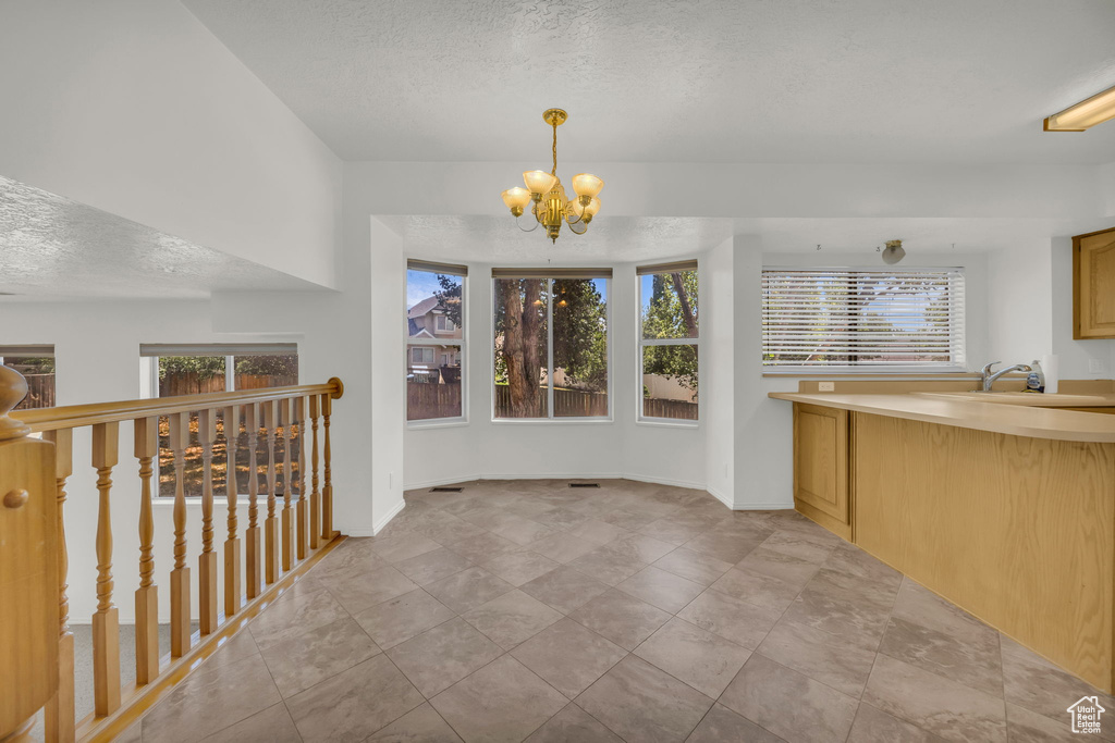 Unfurnished dining area with a textured ceiling and a chandelier