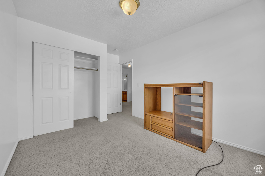 Unfurnished bedroom with carpet floors, a closet, and a textured ceiling
