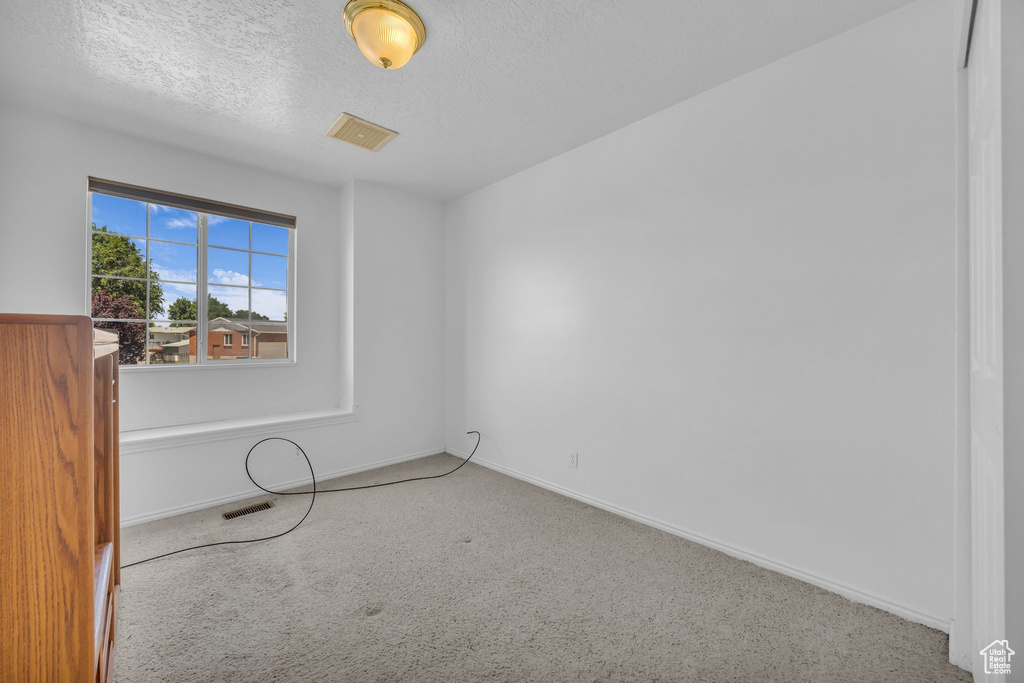 Empty room with carpet flooring and a textured ceiling