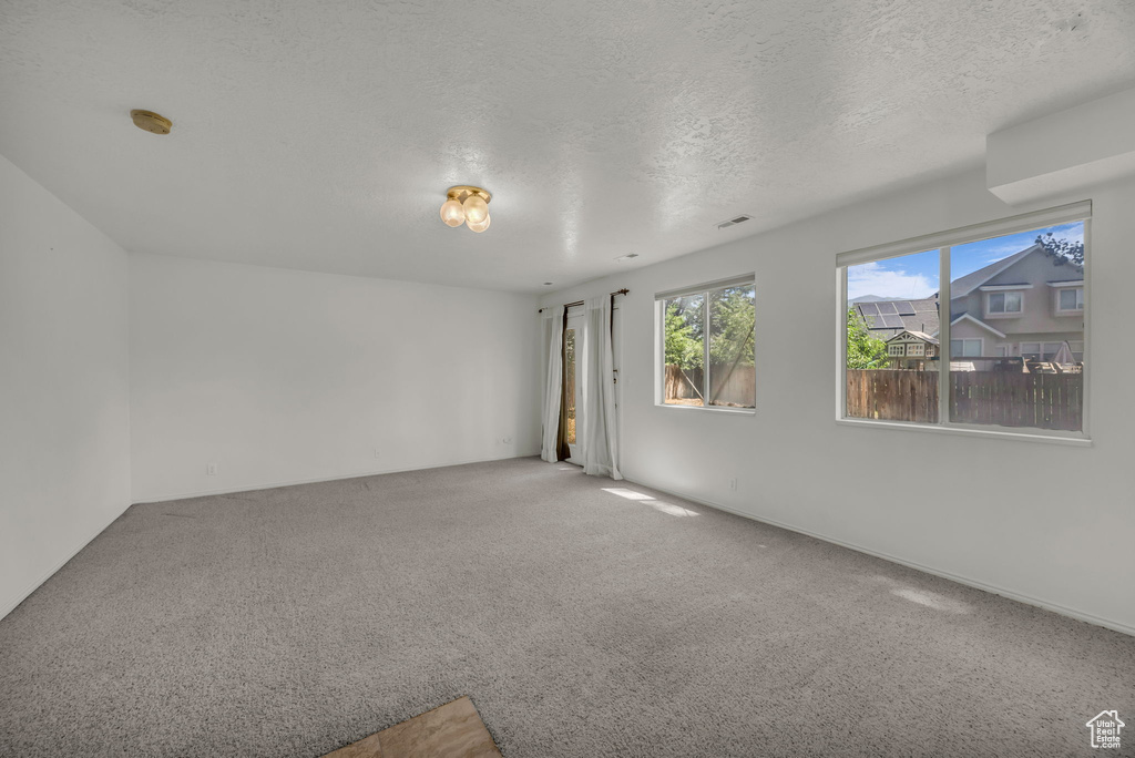 Empty room with carpet flooring and a textured ceiling