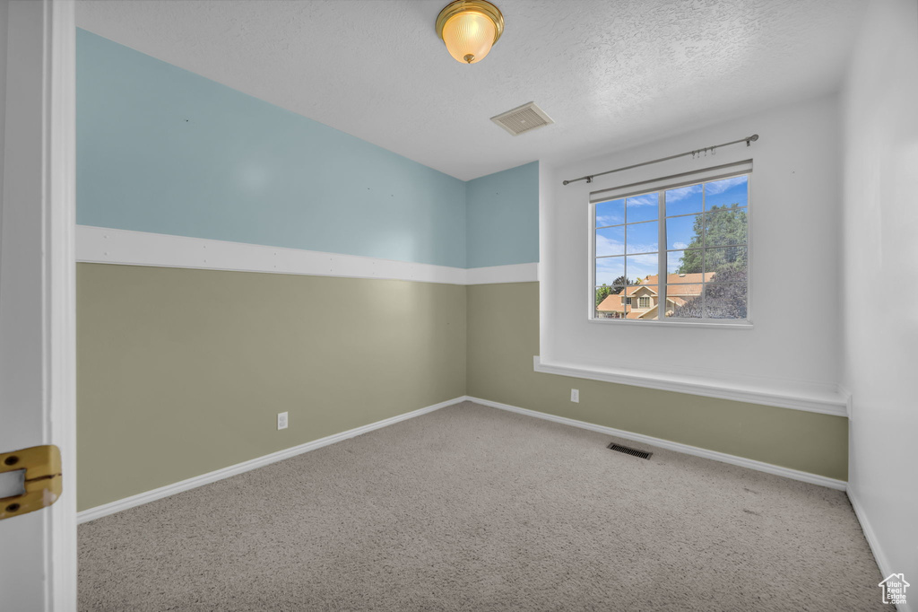 Empty room with carpet flooring and a textured ceiling