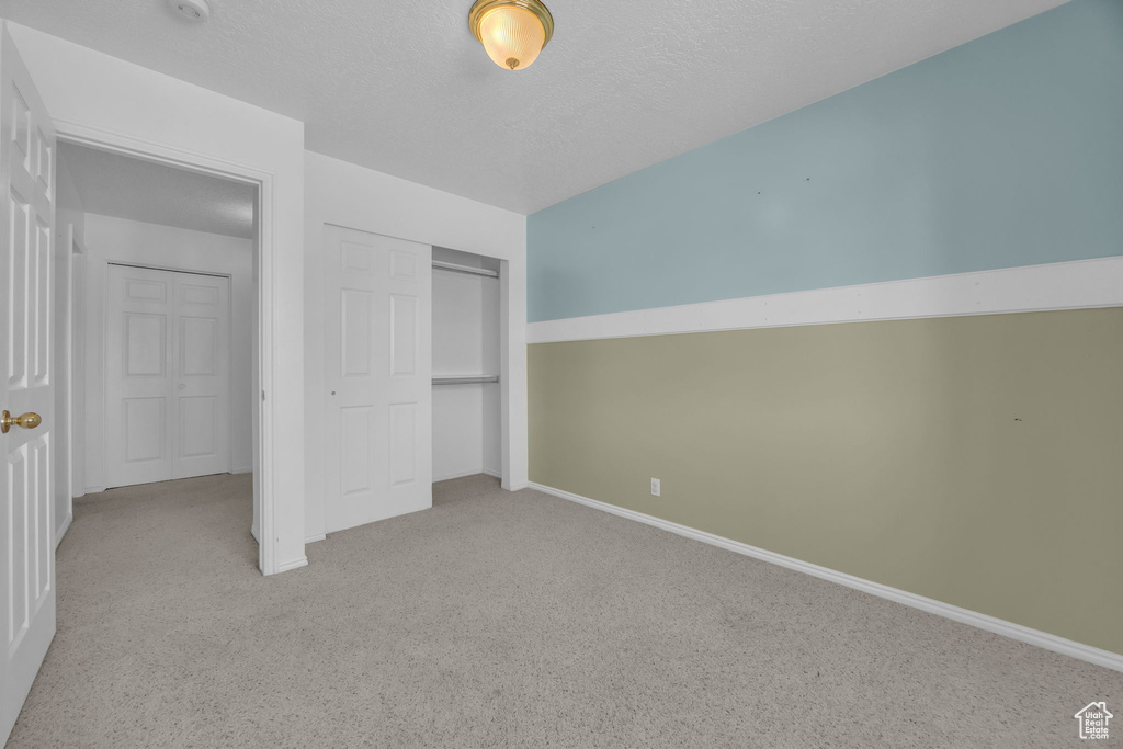 Unfurnished bedroom featuring carpet, a closet, and a textured ceiling