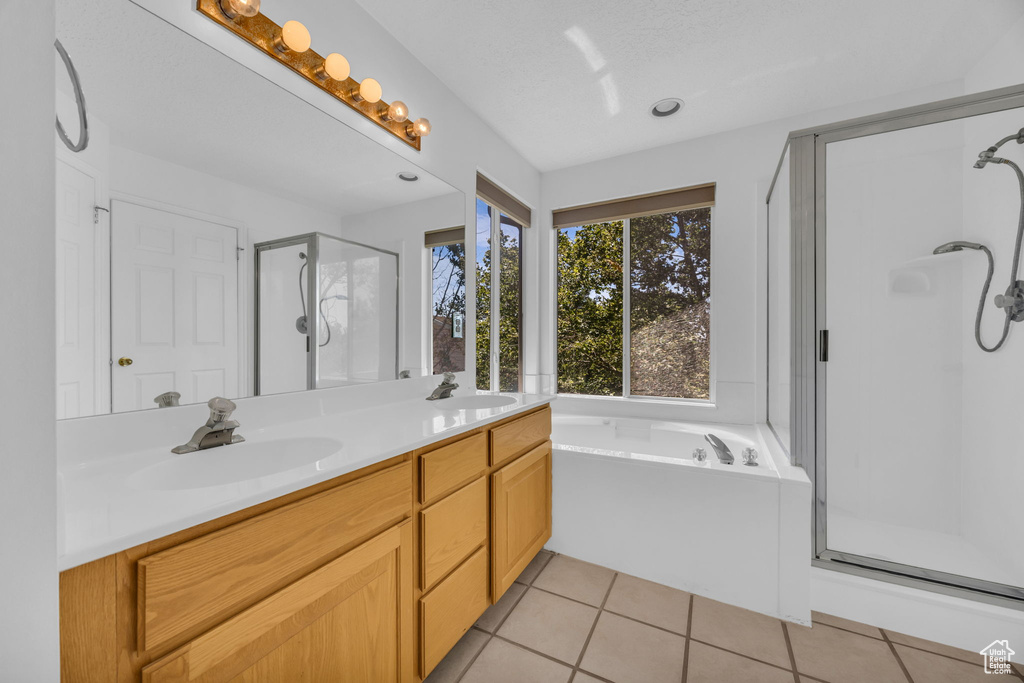 Bathroom featuring a stall shower, double vanity, a garden tub, and tile patterned floors