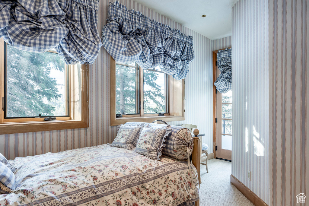Bedroom with wallpapered walls, light colored carpet, and access to exterior