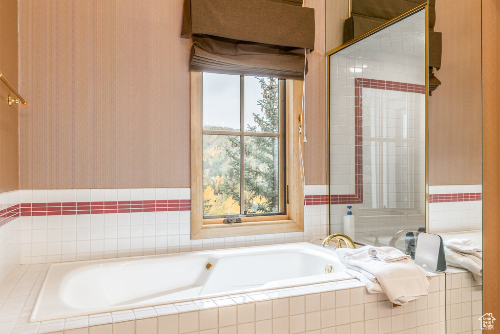 Full bath with a bath and wallpapered walls