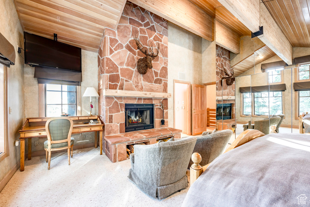 Living area with a stone fireplace, plenty of natural light, a wood ceiling with exposed beams, and high vaulted ceiling