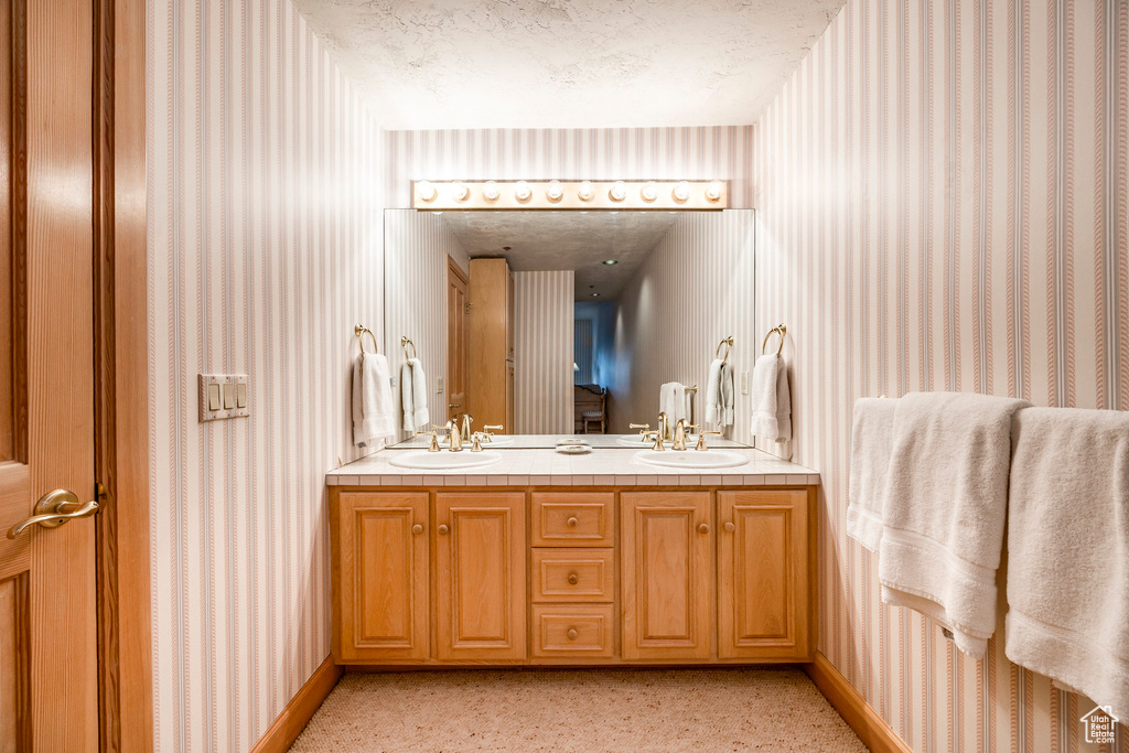 Full bathroom featuring wallpapered walls and double vanity