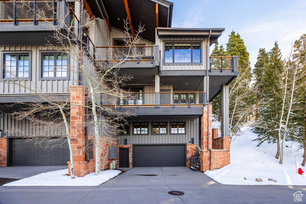 View of front of property featuring a balcony, board and batten siding, a garage, and concrete driveway