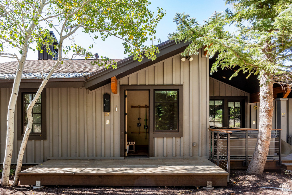 View of exterior entry with board and batten siding and roof with shingles