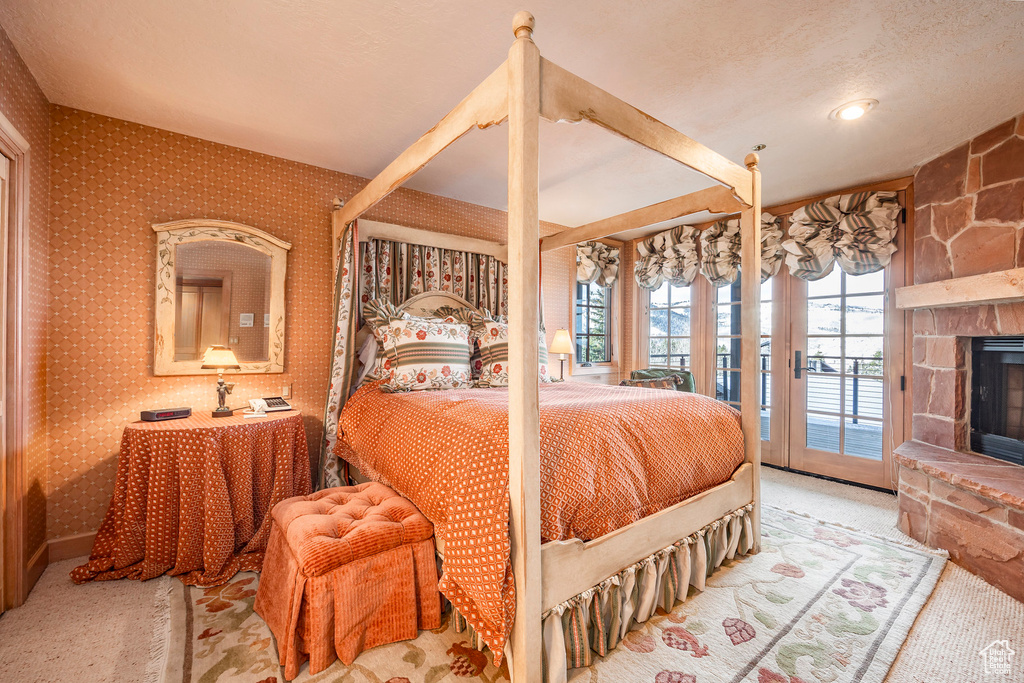 Carpeted bedroom featuring access to exterior, a fireplace, and wallpapered walls