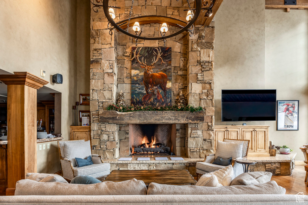 Living room with wood finished floors, a stone fireplace, and a high ceiling