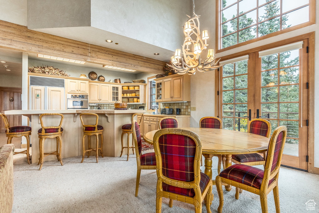 Dining area with a chandelier, recessed lighting, light carpet, a towering ceiling, and french doors
