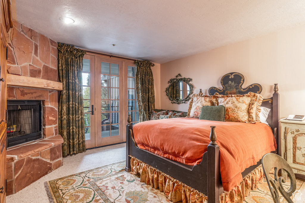 Carpeted bedroom featuring access to exterior, a fireplace, and a textured ceiling