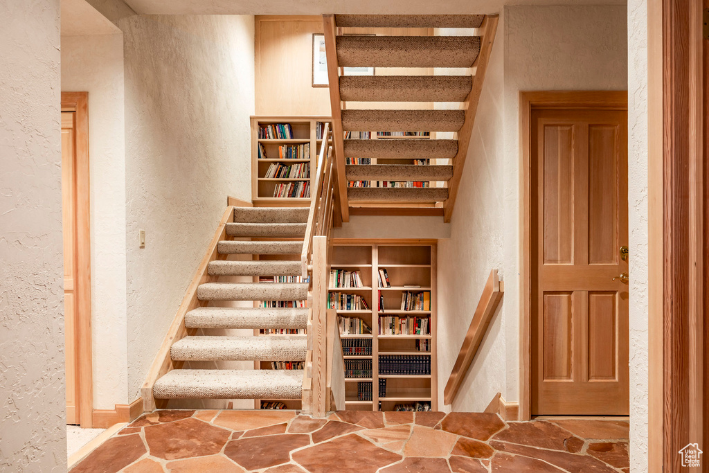 Staircase with a textured wall and stone finish flooring
