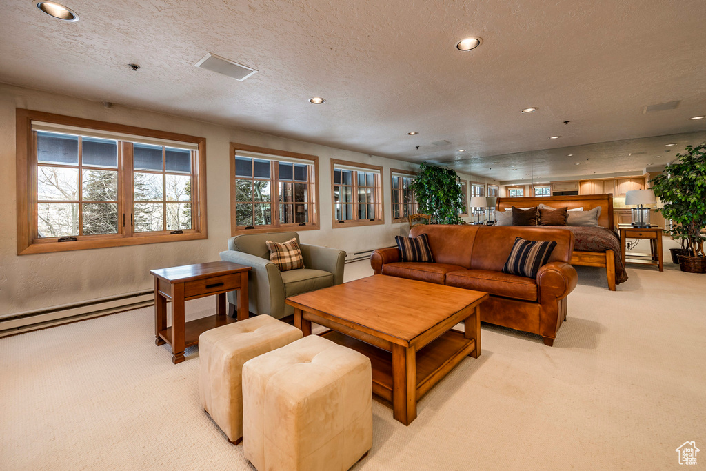 Living area with light carpet, a baseboard heating unit, and recessed lighting