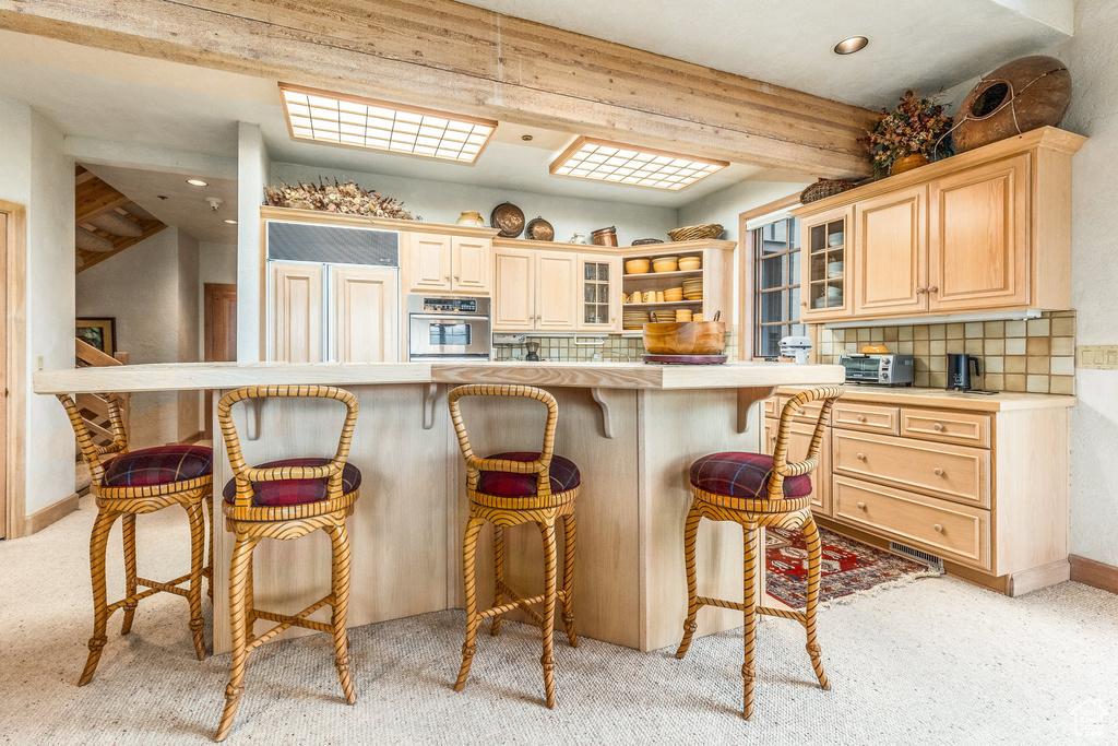 Kitchen featuring stainless steel oven, a kitchen breakfast bar, light carpet, tasteful backsplash, and recessed lighting